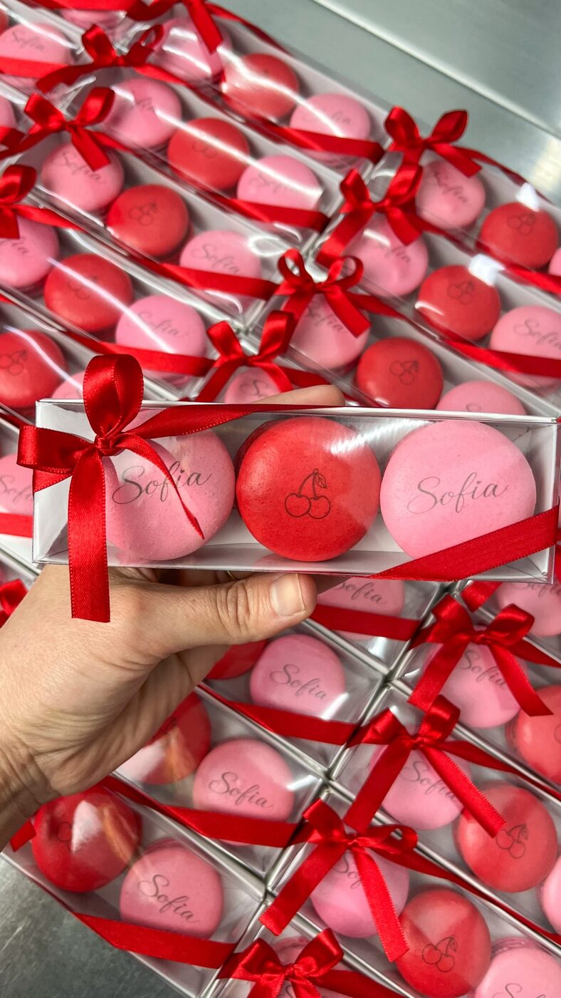 Caixa com três macarons rosa e vermelhos, com o nome Sofia e uma cereja impressos